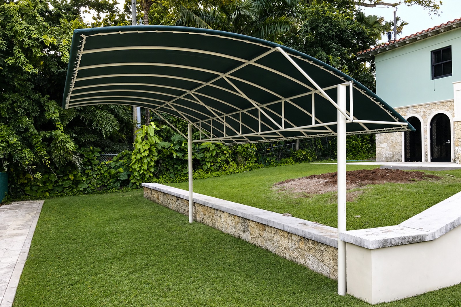 Finished arched cabana with green-and-white striped fabric stretched over the steel frame on an estate lawn at dusk.